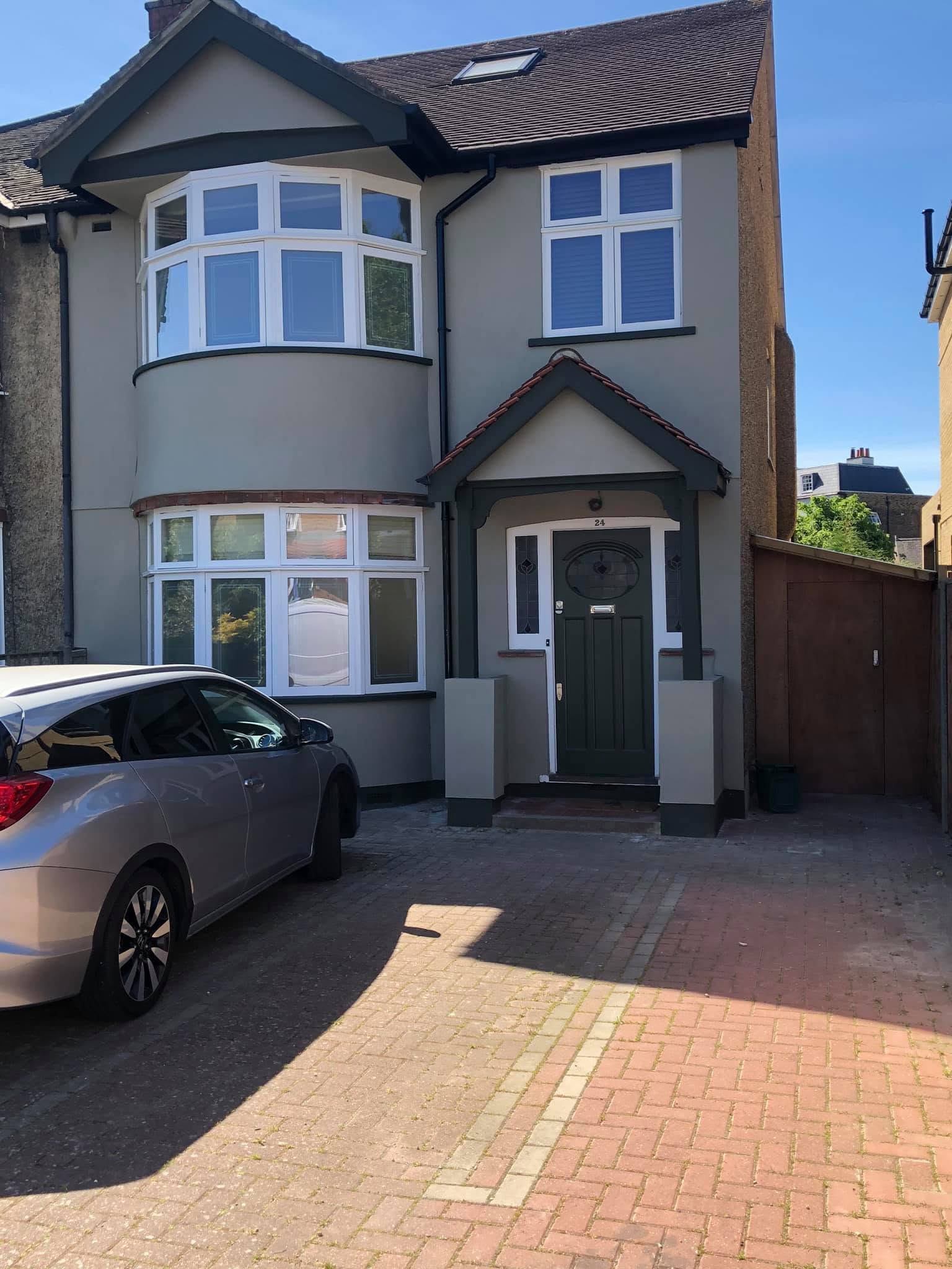 Same house exterior after full render and repaint, smooth sage grey finish